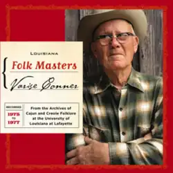 Varise standing with his arms crossed. He is wearing a green plaid shirt.