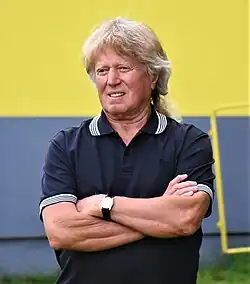 Viktor Sodoma wearing dark polo shirt, standing with arms crossed, squinting to the right of camera