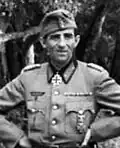 A man wearing a military uniform with an Iron Cross displayed at the front of his uniform collar.