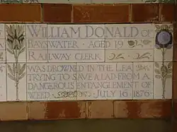 A tablet formed of five tiles of varying sizes, bordered by yellow and blue flowers in an art nouveau style